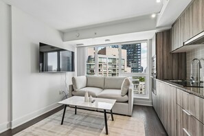 A modern living room with a sofa, a coffee table, and a TV mounted on the wall. - Stylish 1bed 1 bath Central | Pool | Gym (Toronto)