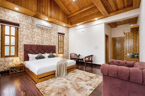 A bedroom with a large bed, wooden ceiling, floral wallpaper, and a fluffy rug. - ELIVAAS Secret Escape Aashiyana 2BHK (Solan)