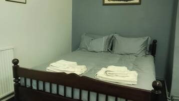 A bedroom with a single bed, two pillows, and a framed picture on the wall.