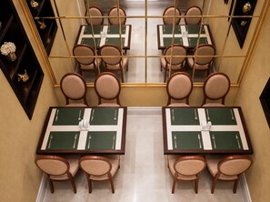 Comedor de hotel con paredes espejadas, varias mesas y sillas.