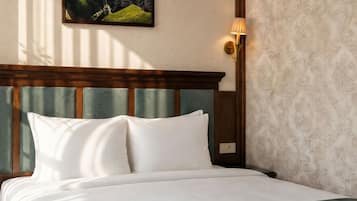 Una cama bien hecha con sábanas blancas, cabecera de madera y una lámpara fijada a la pared.
