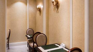 Ein Speiseraum eines Hotels mit einem langen Tisch, Stühlen und wandmontierten Leuchten.