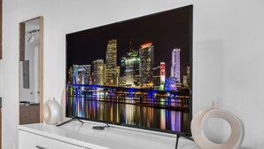 A flat-screen TV mounted on a white cabinet with two decorative vases. - Luxe Condo on Miami River (Miami)