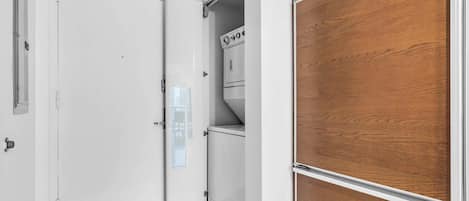 A hallway with a white door, a wooden panel wall, and a white cabinet with a control panel.