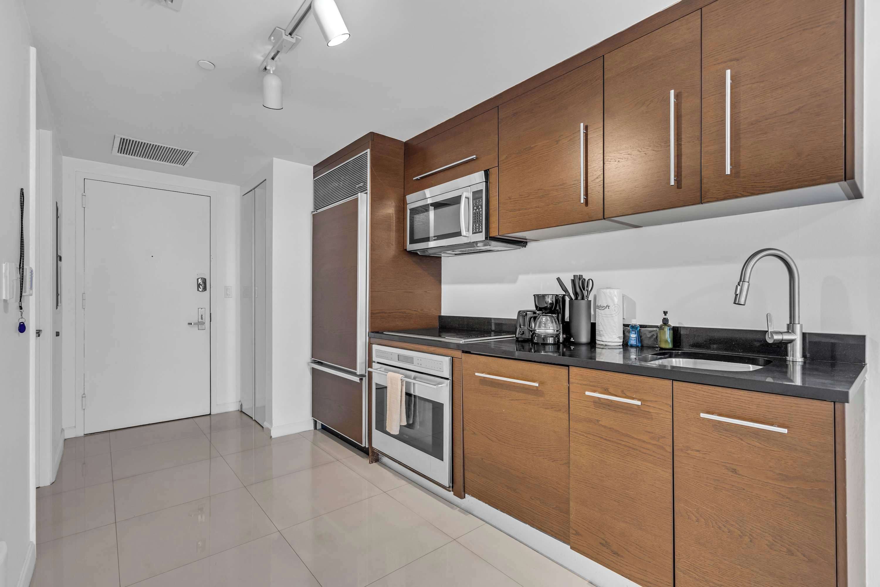 A modern kitchen with wooden cabinets, stainless steel appliances, and a black countertop.