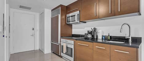 Una cocina moderna con armarios de madera, electrodomésticos de acero inoxidable y una encimera negra.