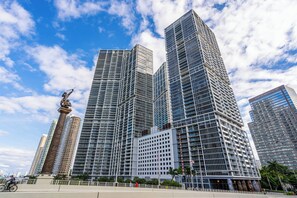 A modern high-rise building with a grid-like facade, surrounded by other tall buildings and a clear sky. - Luxe Condo on Miami River (Miami)