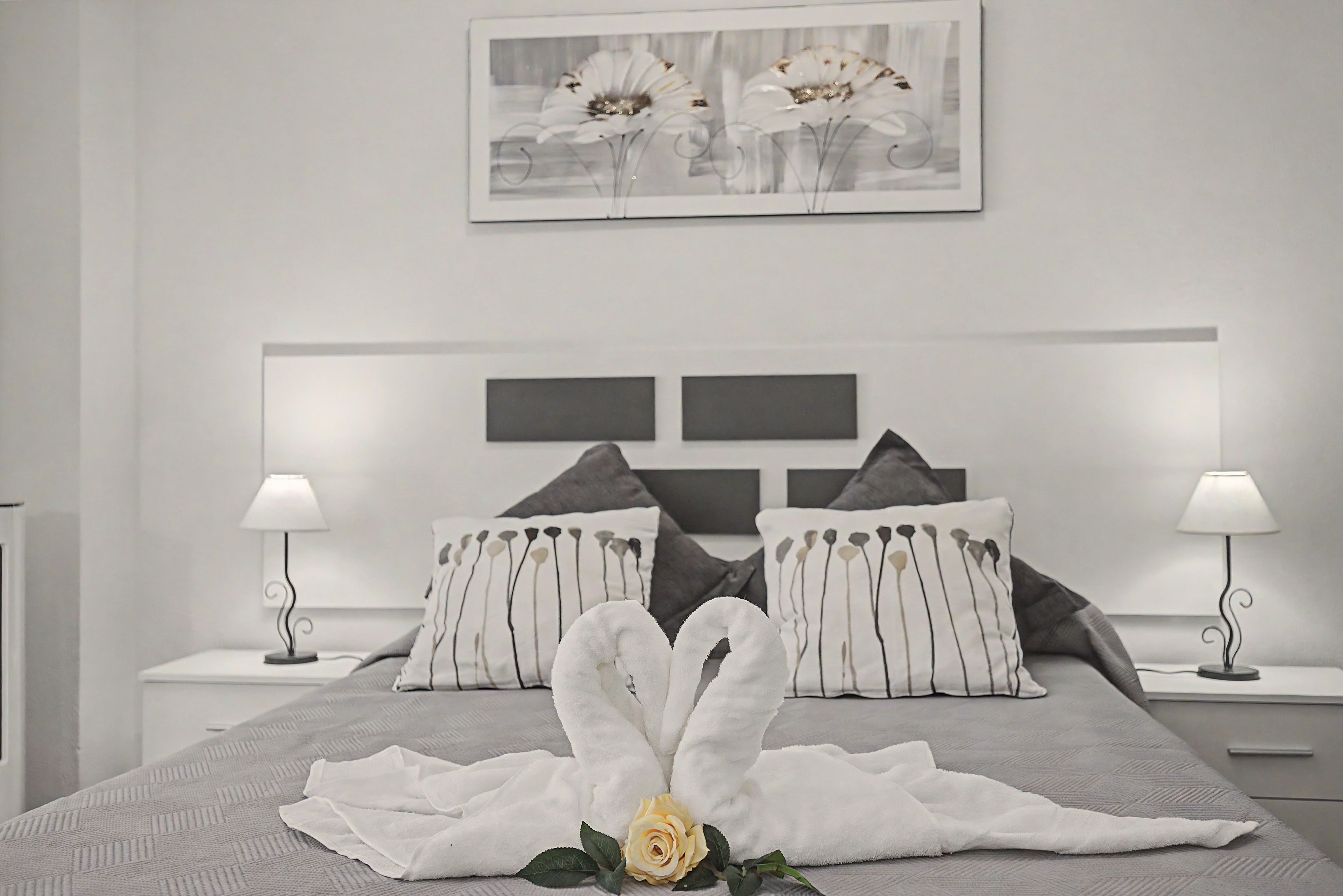 Ein modernes Schlafzimmer mit einem großen Bett, zwei Nachttischlampen und einem gerahmten Kunstwerk darüber.