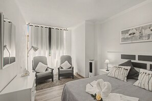 Ein Hotelzimmer mit einem Bett, zwei Stühlen, einem Nachttisch, einer Lampe und einem Bild an der Wand.