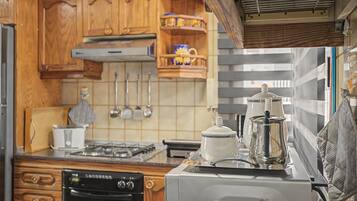 Cocina compacta con armarios de madera, estufa a gas, horno empotrado y cafetera.