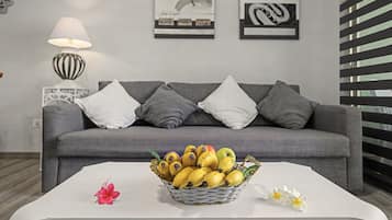 Ein Wohnzimmer mit einem grauen Sofa, einem weißen Couchtisch und einer Bananenkiste.