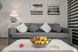 Ein Wohnzimmer mit einem grauen Sofa, einem weißen Couchtisch und einer Bananenkiste.