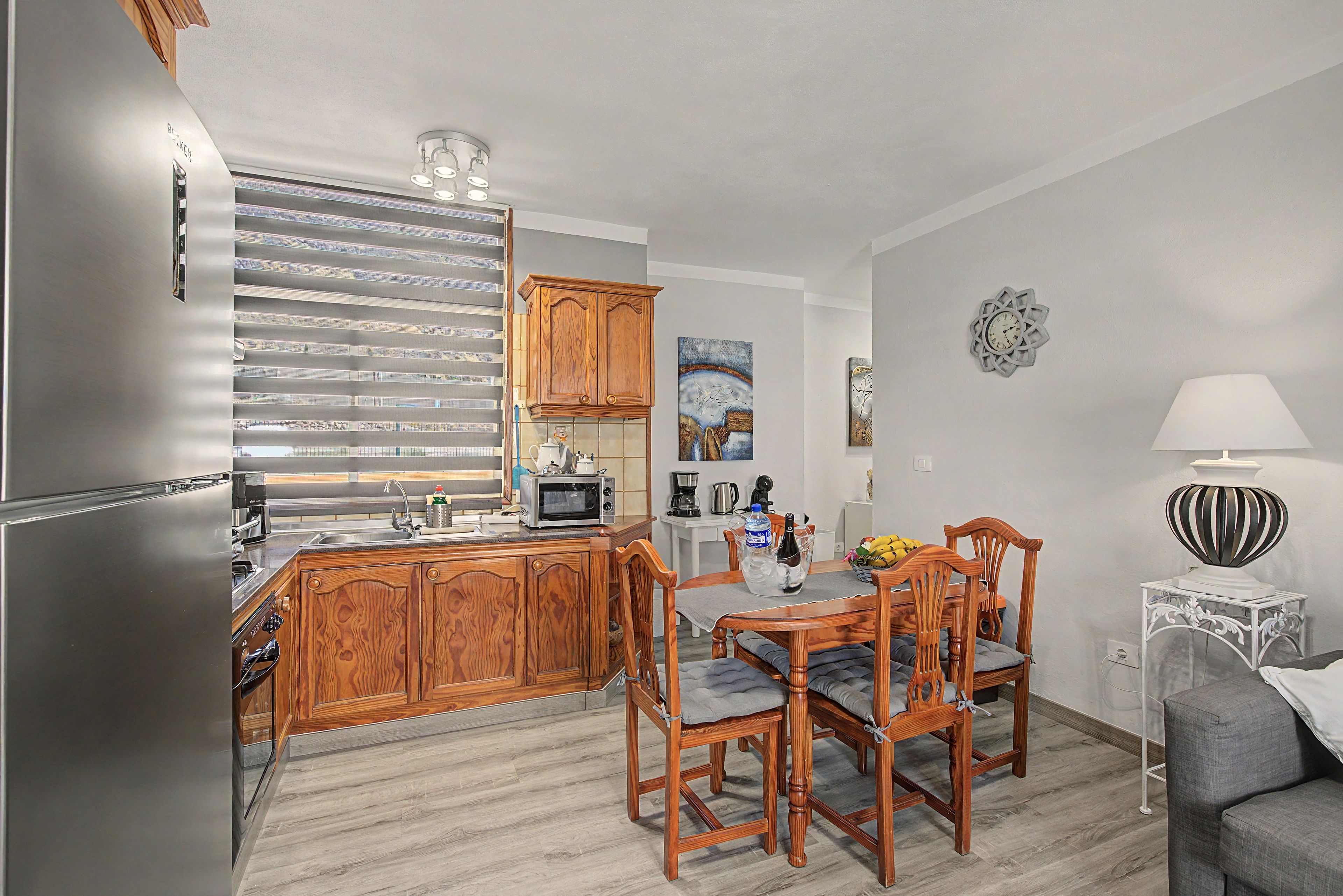 Una cocina moderna con armarios de madera, microondas integrado y un comedor con mesa y sillas.