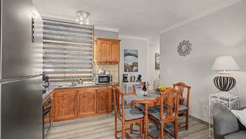 Una cocina moderna con armarios de madera, microondas integrado y un comedor con mesa y sillas.