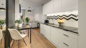 A modern kitchen with white cabinetry, a black countertop, and a zigzag patterned backsplash. - Dwie Motławy 59 | Riverside | Perfect Stay (Gdańsk)