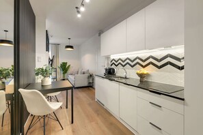 Eine moderne Küche mit weißen Schränken, einer schwarzen Arbeitsplatte und einer Spritzschutzwand mit Zickzackmuster.