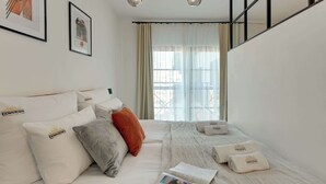 A hotel room with a bed, pillows, a magazine, and a window with curtains. - Dwie Motławy 59 | Riverside | Perfect Stay (Gdańsk)