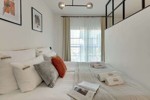 Ein Hotelzimmer mit Bett, Kissen, einer Zeitschrift und einem Fenster mit Vorhängen.