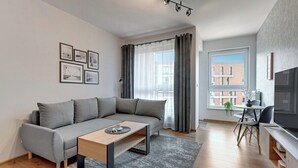 Una sala moderna con un sofá gris, una mesa de centro de madera y un comedor con mesa y sillas.