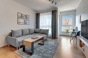 A modern living room with a grey sofa, a wooden coffee table, and a dining area with a table and chairs. - City Center | Bastion Wałowa 59 with Balcony (Gdańsk)