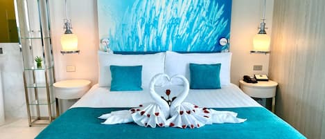 A hotel room with a large bed, two bedside tables, a wall-mounted light fixture, and a large window.