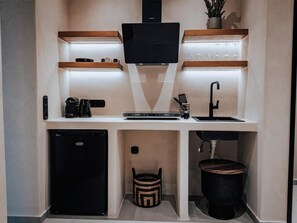 Eine kompakte Küchenzeile mit eingebautem Herd, einer Kaffeemaschine, einem Spülbecken und einem kleinen Kühlschrank.
