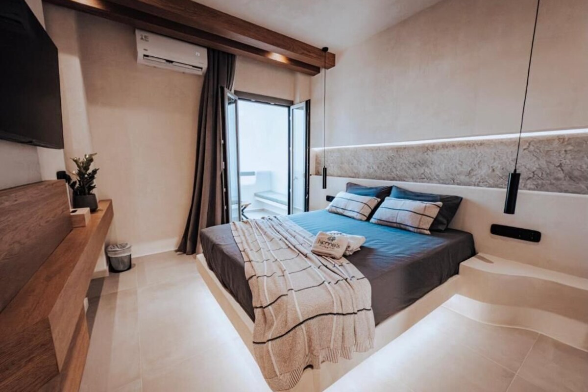 A modern bedroom with a bed, bedside table, and a view of the outdoors.