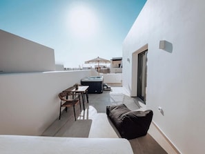 Terraço no terraço com área de refeições, banheira de hidromassagem e um sofá.