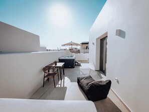 Un balcón moderno con jacuzzi, asientos y vistas a la ciudad.