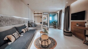A modern living room with a sofa, a coffee table, and a TV mounted on the wall. - Nonna's Suites (Naxos)