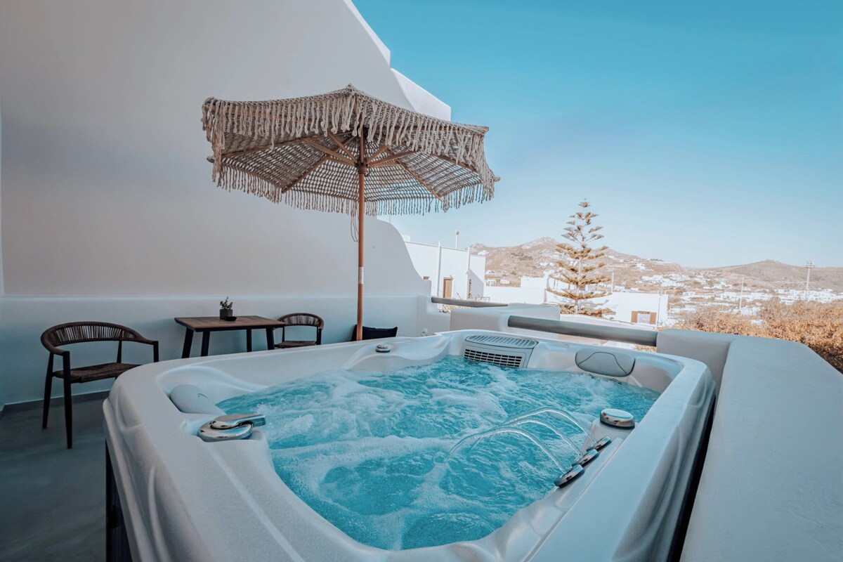 A hot tub with a view of a white building and a mountain in the background.