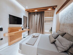 Ein modernes Schlafzimmer mit einem Bett, einem an der Wand montierten Fernseher, einem Nachttisch und einem Fenster mit Vorhängen.