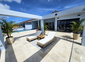 Un espace de détente extérieur moderne, doté d’une piscine, de chaises longues et de plantes en pot.