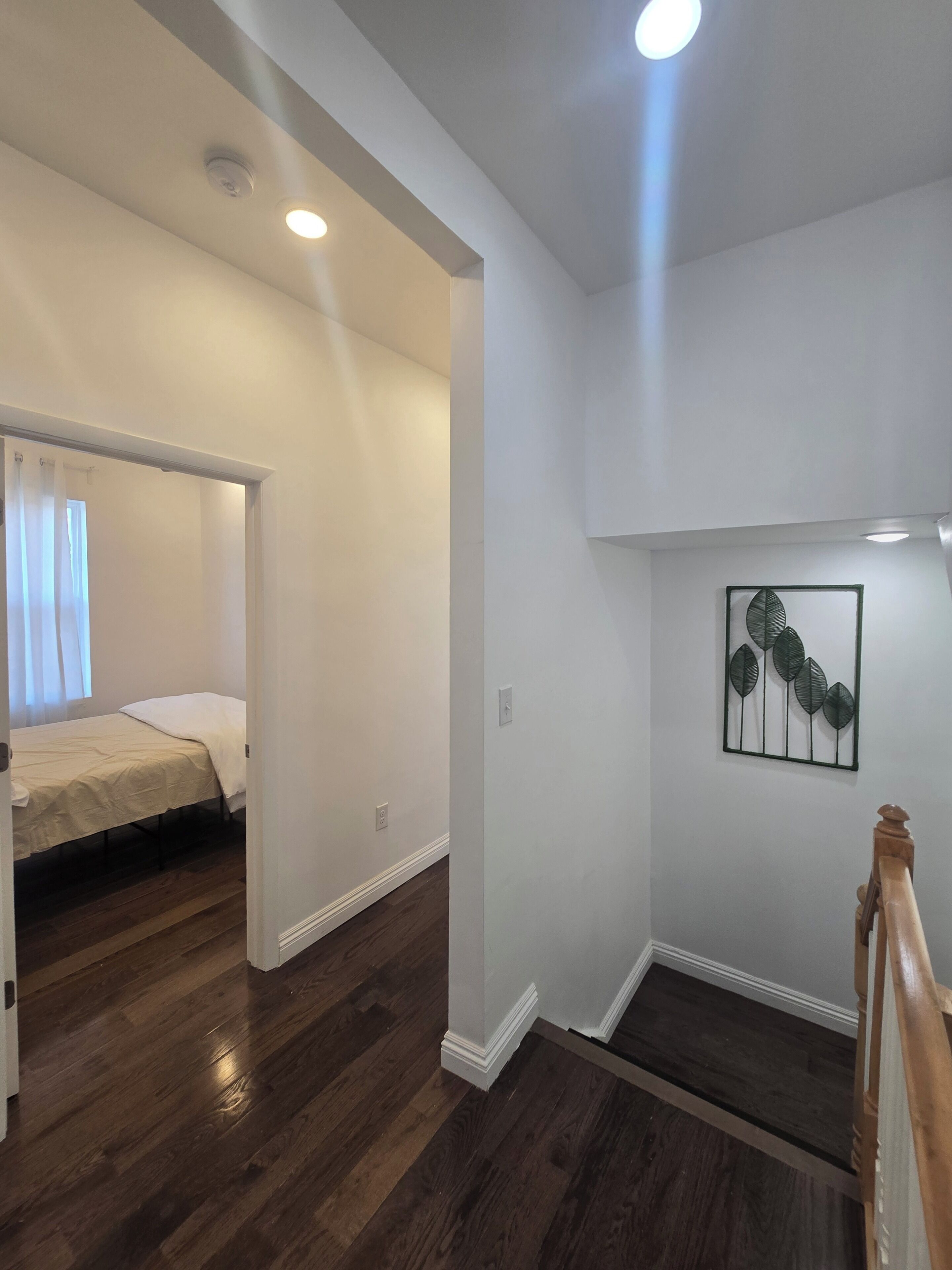 A room with a bed, a staircase, and a wall-mounted artwork.