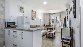 A modern kitchen with a built-in island, a dining area with a table and chairs, and a living space with a sofa and a TV.