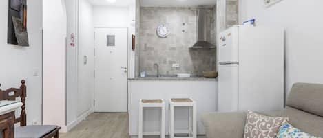 Cocina compacta con un reloj, un refrigerador y un lavamanos.