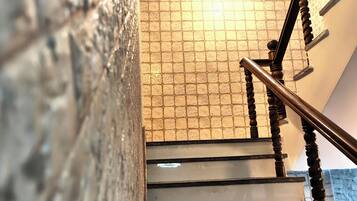 A staircase with a wooden handrail and a textured wall.