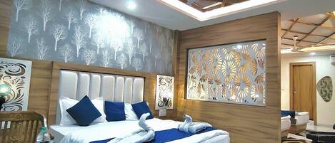 A modern hotel room with a bed, a dining table, and a ceiling with a geometric light fixture.
