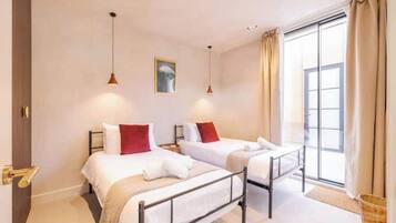 A hotel room with two beds, a window with curtains, and a painting on the wall.