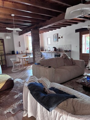 A cozy living room with a large sofa, a small table, and a kitchen in the background. - Country house 45 minutes from Toulouse. Pets Allowed (Saint-Urcisse)