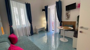 A modern living room with a sofa, a dining table, and a kitchen area. - Sweet Home Luna: a charming apartment in the heart of Amalfi (Amalfi)