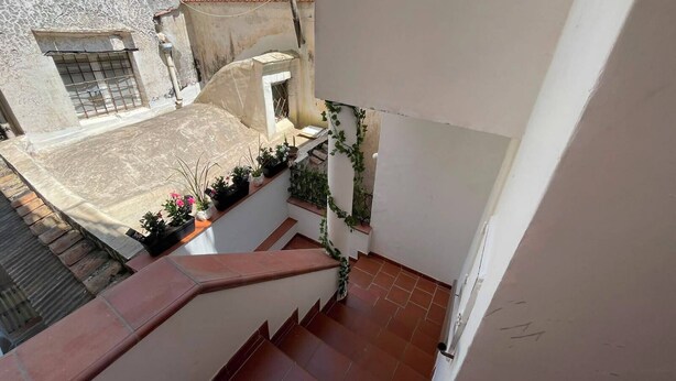 A residential balcony with a tiled floor, a small window with bars, and potted plants. - Sweet Home Luna: a charming apartment in the heart of Amalfi (Amalfi)