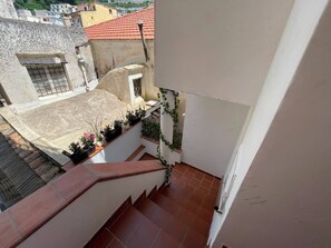 A residential balcony with a tiled floor, a small window with bars, and potted plants. - Sweet Home Luna: a charming apartment in the heart of Amalfi (Amalfi)