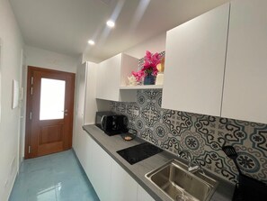 A narrow kitchen with a built-in sink, a coffee maker, and a decorative vase on the countertop. - Sweet Home Luna: a charming apartment in the heart of Amalfi (Amalfi)