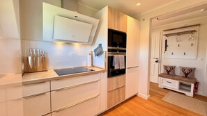 A modern kitchen with built-in appliances, wooden cabinets, and a countertop with knives. - HarzElegance – 2 Bedrooms, Balcony and Fireplace (Walkenried)