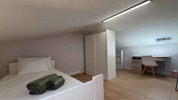 Un dormitorio con cama, escritorio y armario.