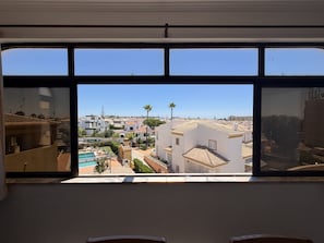 A view from a window with a clear sky, a pool, and buildings in the distance. - Gale Beach Walk T3 Apartment (Albufeira)