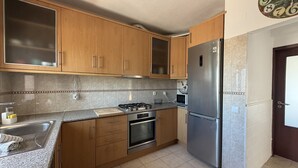 Una cocina con armarios de madera, un refrigerador de acero inoxidable, una estufa y un microondas.