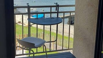 Een balkon met uitzicht op een haven, een klein rond tafeltje en een stoel.