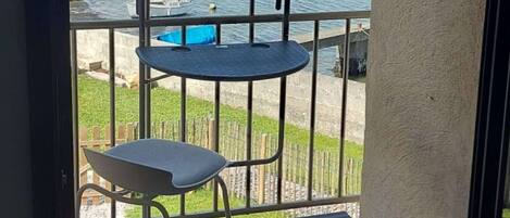 Een balkon met uitzicht op een haven, een klein rond tafeltje en een stoel.